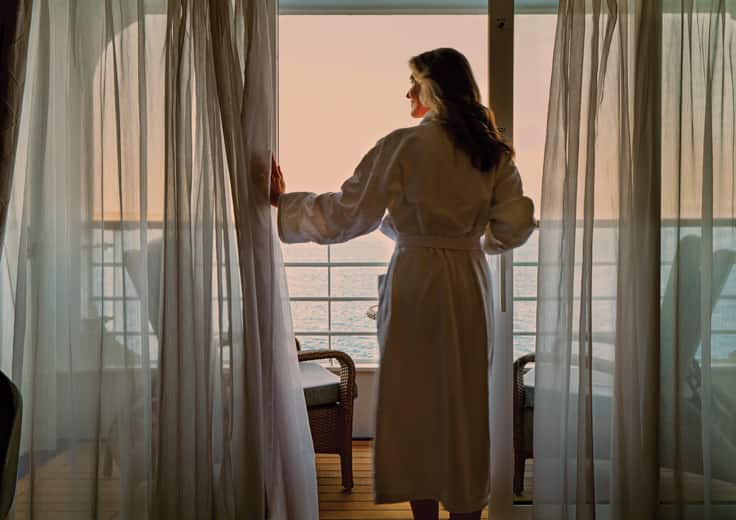 Woman looking out over her balcony onboard Oceania Cruises