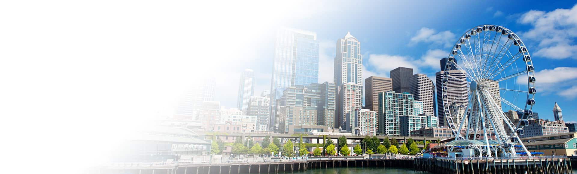 See the day time skyline of  Seattles' Great Wheel in Elliot Bay on an overnight hotel stay with Oceania Cruises.