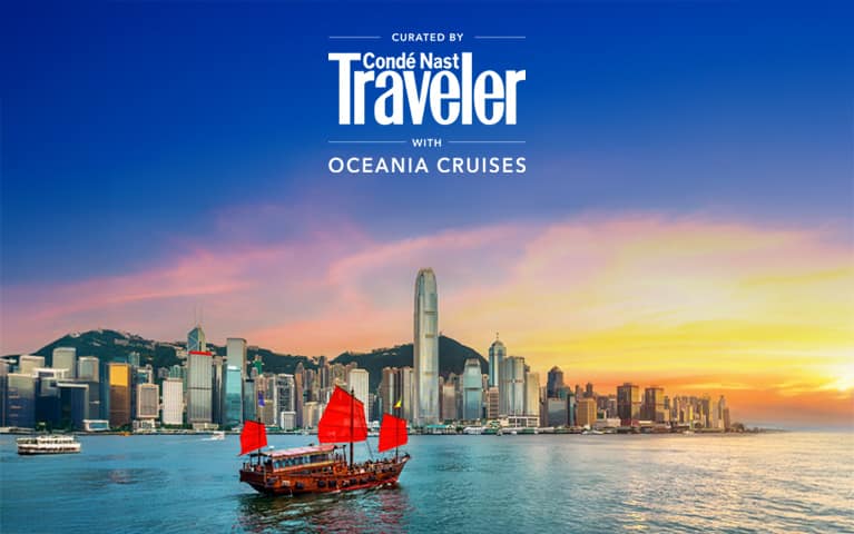 Traditional red-sailed junk boat sailing across Victoria Harbour with the Hong Kong skyline and a golden sunset in the background.