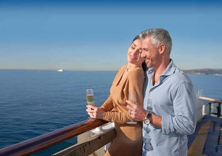Couple on cruise balcony drinking champagne, Oceania Cruises