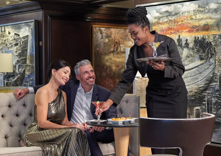Shipboard Gratuities included on Oceania Cruises. Couple having drinks with personalized service.